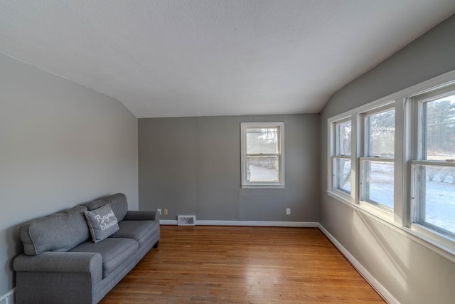 living room featuring a textured ceiling, lofted ceiling, and hardwood / wood-style flooring