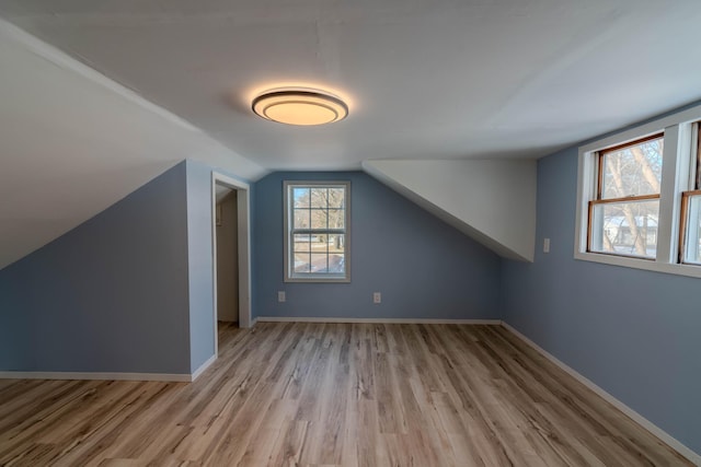 additional living space with light wood-type flooring and vaulted ceiling