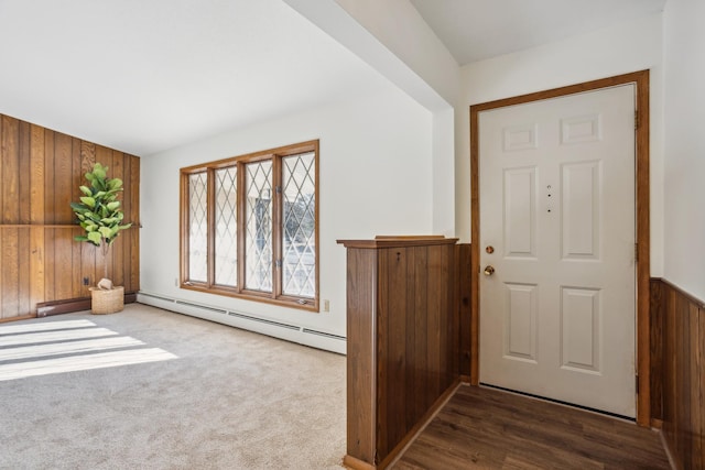 entrance foyer with dark colored carpet, a baseboard radiator, and wooden walls