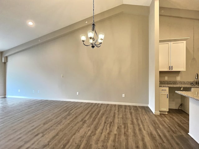 unfurnished dining area with sink, dark hardwood / wood-style flooring, lofted ceiling, and a notable chandelier