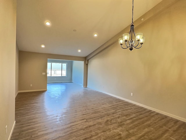 empty room featuring a chandelier, dark wood-type flooring, and lofted ceiling