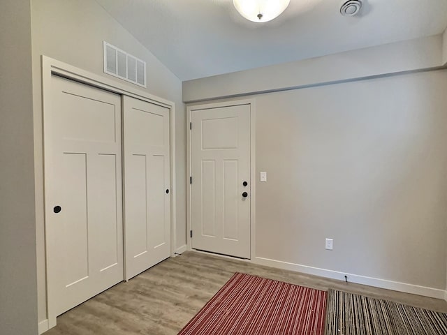 foyer entrance with light hardwood / wood-style floors and lofted ceiling