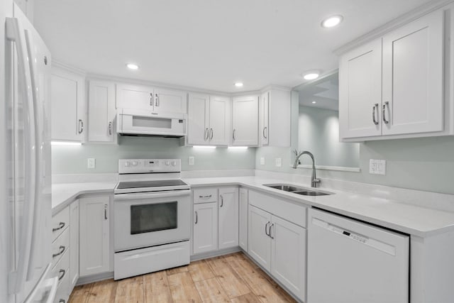 kitchen featuring white cabinets, white appliances, light hardwood / wood-style flooring, and sink