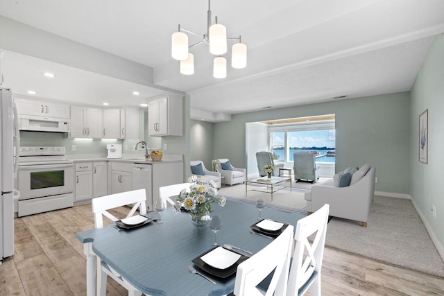 dining space featuring sink, light hardwood / wood-style flooring, and an inviting chandelier