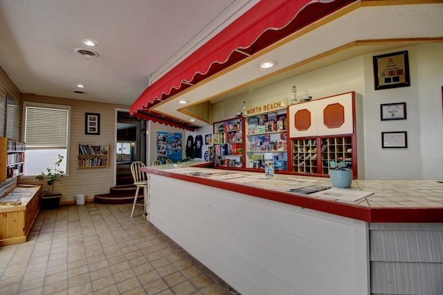 interior space featuring a textured ceiling, tile countertops, and light tile patterned flooring