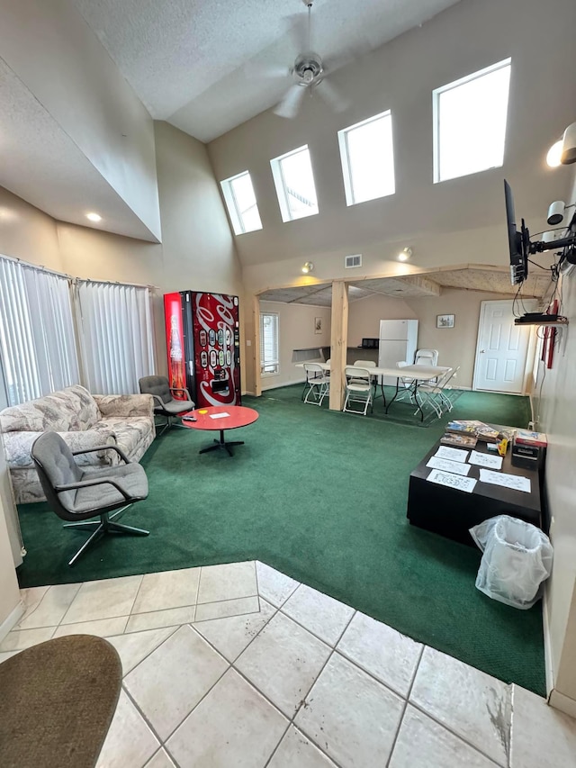 interior space with carpet flooring, ceiling fan, a textured ceiling, and a high ceiling