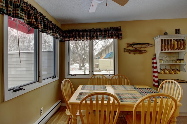 dining room with hardwood / wood-style floors, a textured ceiling, a baseboard radiator, and ceiling fan