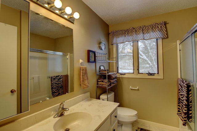 bathroom featuring vanity, a textured ceiling, toilet, and a shower with shower door