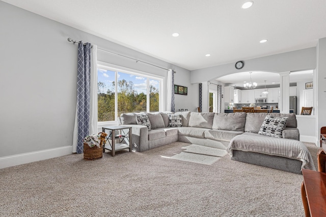 living room with an inviting chandelier, carpet flooring, and decorative columns