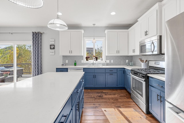 kitchen featuring pendant lighting, sink, appliances with stainless steel finishes, white cabinetry, and blue cabinets