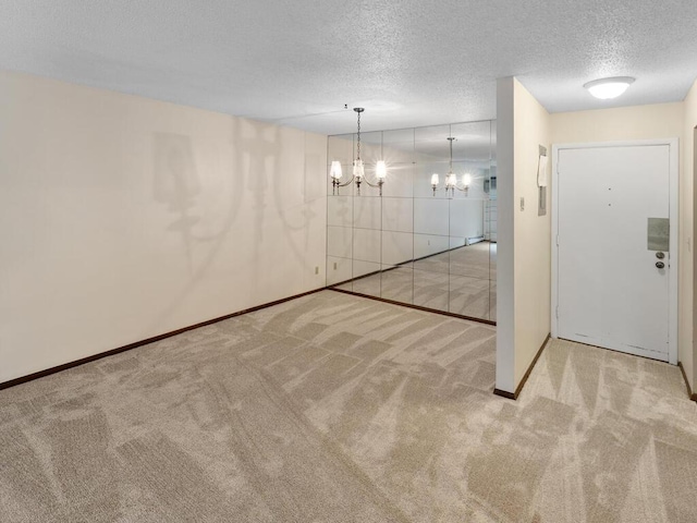 unfurnished room with light carpet, a textured ceiling, and a chandelier