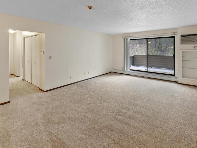 empty room with a textured ceiling, light colored carpet, and a baseboard heating unit