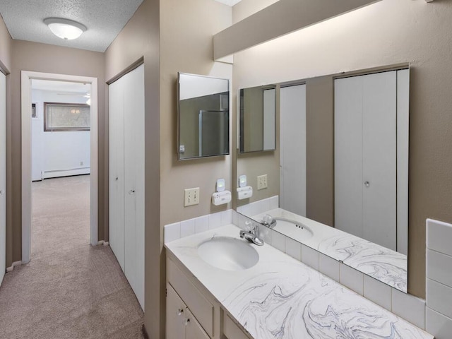 bathroom with a textured ceiling, vanity, and baseboard heating