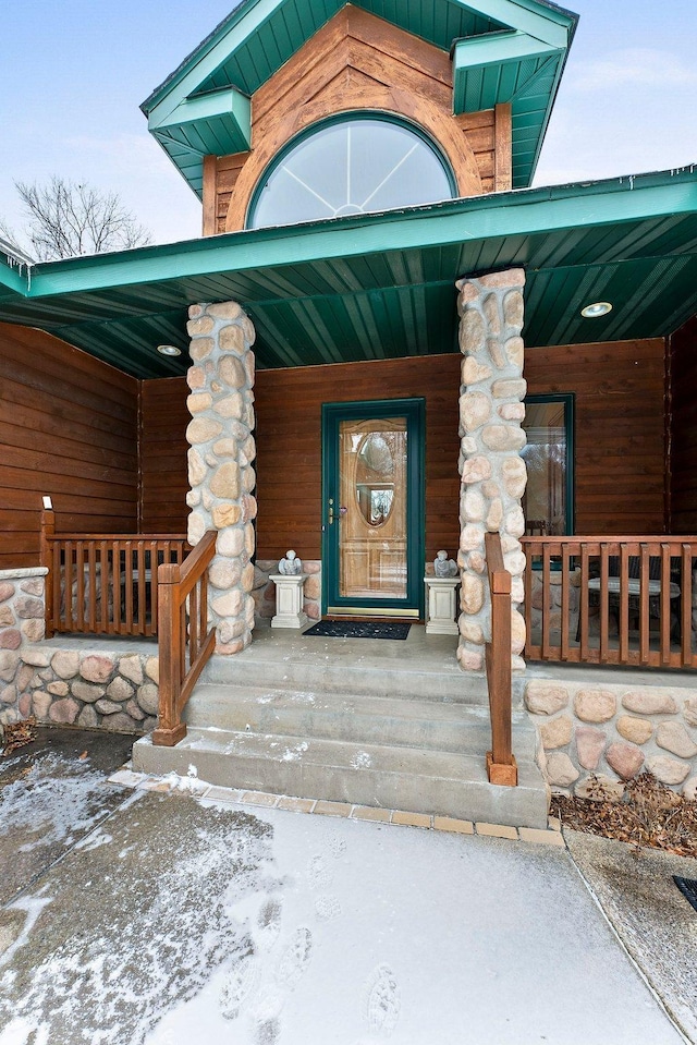 snow covered property entrance with a porch