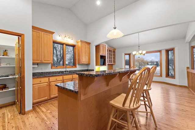 kitchen with a breakfast bar, light wood-style flooring, a sink, a kitchen island, and a chandelier