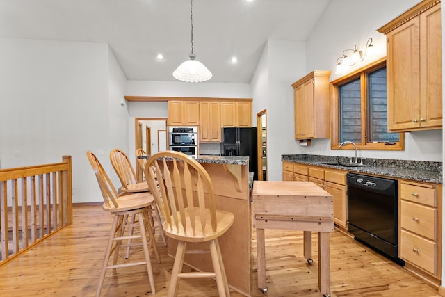 kitchen featuring light brown cabinetry, sink, hanging light fixtures, dark stone counters, and black appliances