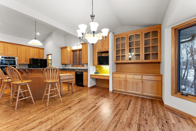 kitchen featuring stainless steel double oven, a breakfast bar, vaulted ceiling, black refrigerator, and built in desk