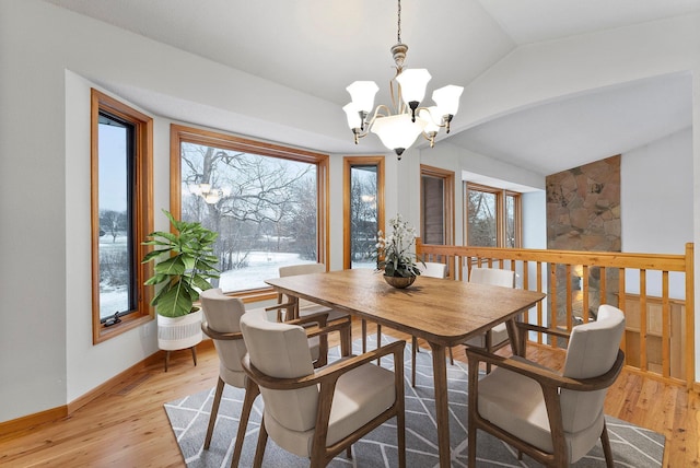 dining space with baseboards, light wood-style floors, a chandelier, and vaulted ceiling