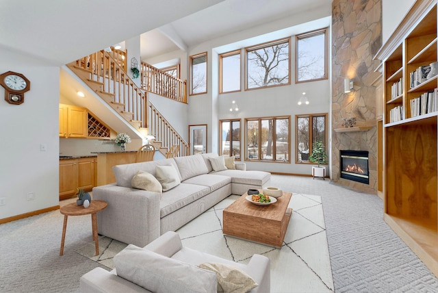 living area with stairs, baseboards, light carpet, and a fireplace