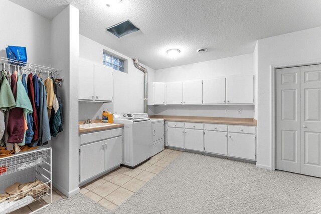 laundry room with sink, cabinets, light tile patterned floors, independent washer and dryer, and a textured ceiling