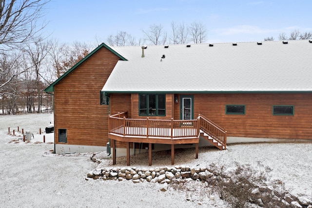 snow covered rear of property featuring roof with shingles and a wooden deck