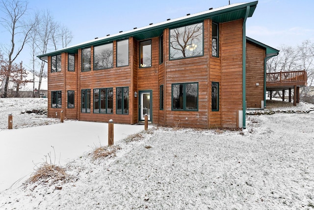 snow covered back of property with a deck