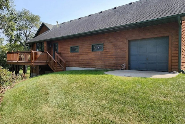 rear view of house featuring a lawn, roof with shingles, a deck, and driveway