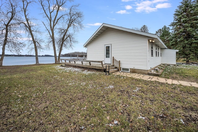 back of house with a yard and a deck with water view