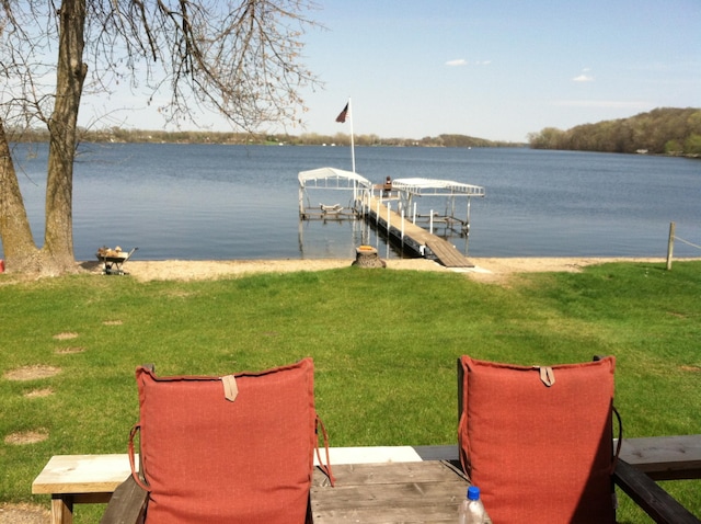 dock area with a lawn and a water view