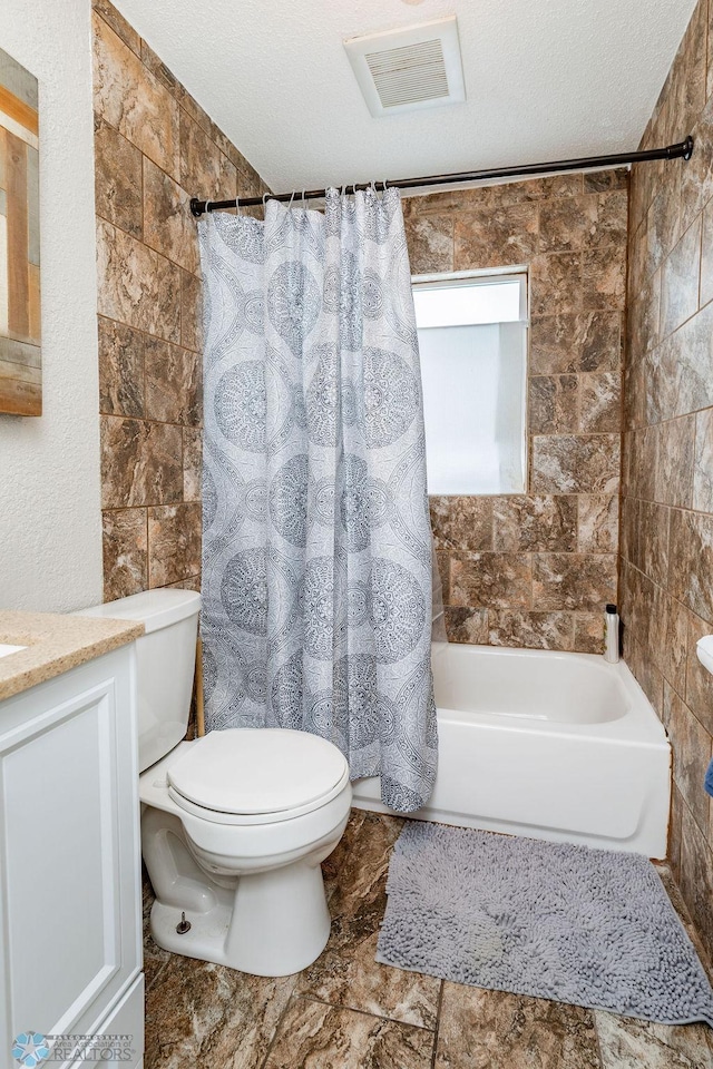 full bathroom featuring vanity, toilet, a textured ceiling, and shower / tub combo with curtain