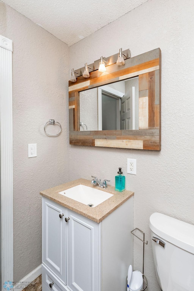 bathroom featuring vanity, toilet, and a textured ceiling