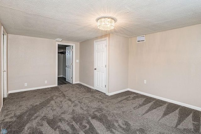 carpeted empty room with a textured ceiling and an inviting chandelier