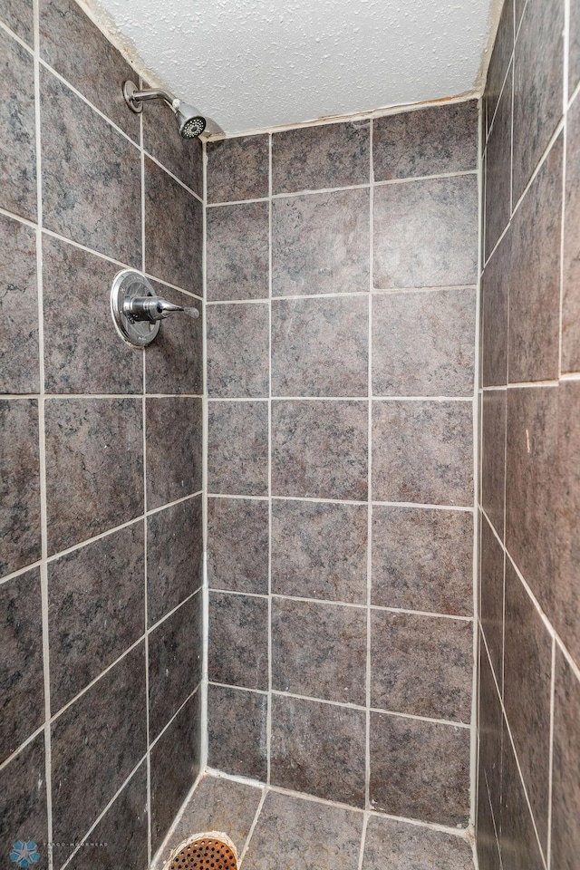 bathroom featuring a tile shower and a textured ceiling