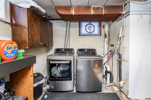 clothes washing area with washing machine and clothes dryer and cabinets