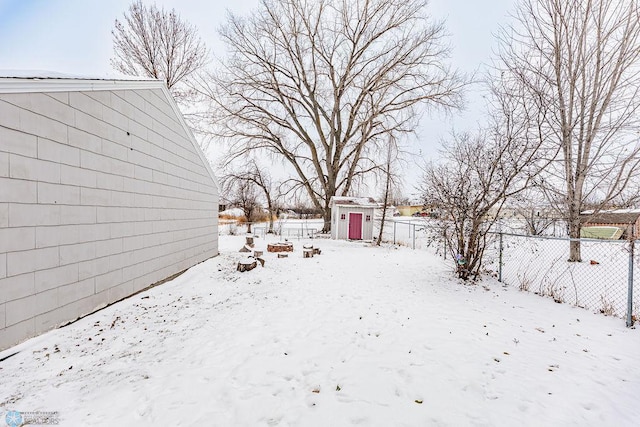 yard layered in snow featuring a storage shed