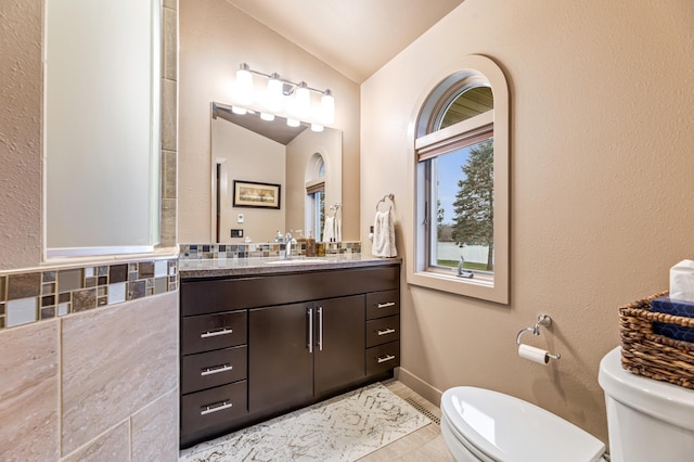 bathroom featuring tile patterned flooring, lofted ceiling, toilet, decorative backsplash, and vanity