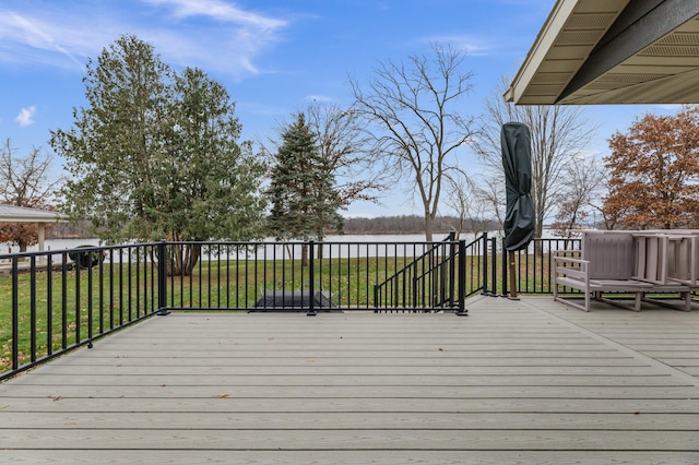 wooden deck featuring a water view and a lawn