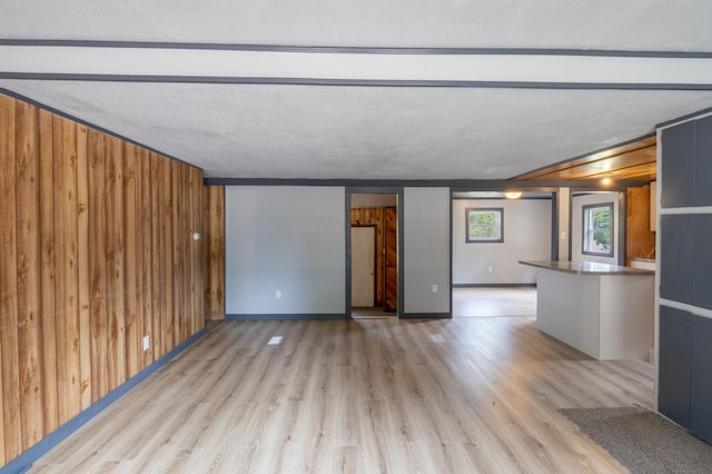 unfurnished living room with wood walls and light wood-type flooring