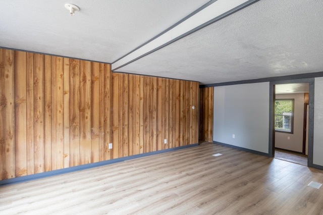 empty room featuring hardwood / wood-style floors, a textured ceiling, and wooden walls