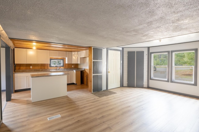 kitchen featuring a kitchen island, white cabinetry, a textured ceiling, and light hardwood / wood-style flooring