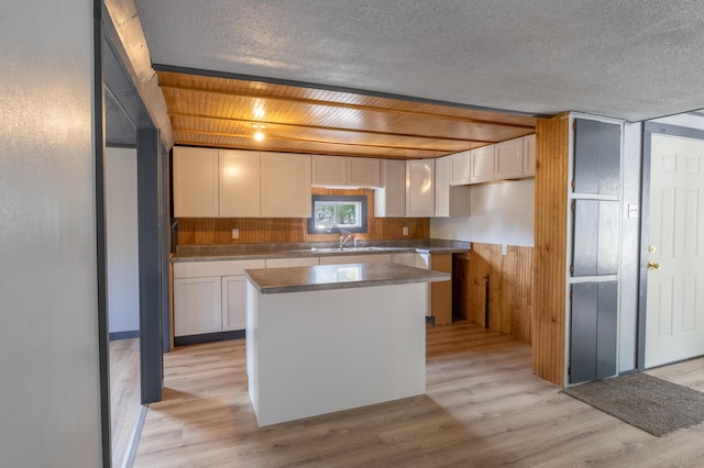 kitchen with light hardwood / wood-style floors, a center island, white cabinetry, and sink