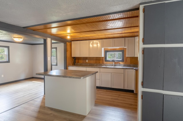 kitchen with white cabinets, a center island, light hardwood / wood-style floors, and sink