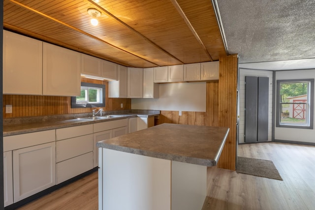 kitchen featuring wood walls, a center island, white cabinets, and light wood-type flooring