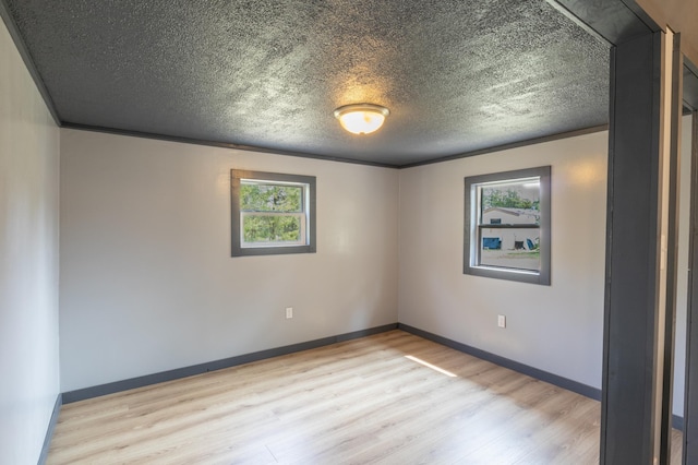 unfurnished room with light hardwood / wood-style floors, a textured ceiling, and a wealth of natural light