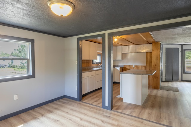 kitchen featuring a center island, a healthy amount of sunlight, a textured ceiling, and light hardwood / wood-style flooring