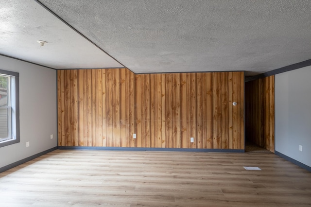 spare room featuring hardwood / wood-style floors, a textured ceiling, and wood walls