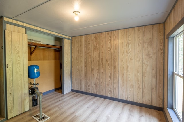 unfurnished bedroom featuring wood walls, light wood-type flooring, and a closet