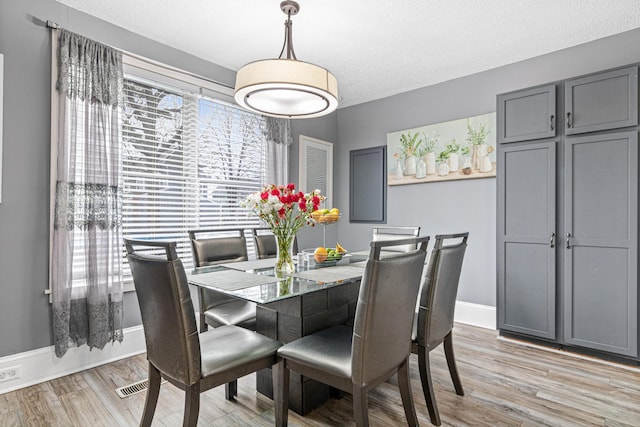 dining space with a textured ceiling and light wood-type flooring