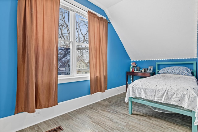 bedroom featuring wood-type flooring, vaulted ceiling, and multiple windows