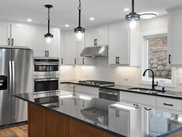 kitchen with white cabinets, stainless steel appliances, dark stone counters, and sink